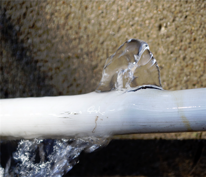 a white pipe that has burst and has water leaking from it